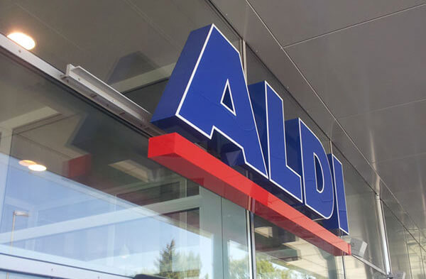 Leuchbuchstaben Aldi-Schriftzug an der Glas-Fassade über dem Eingang